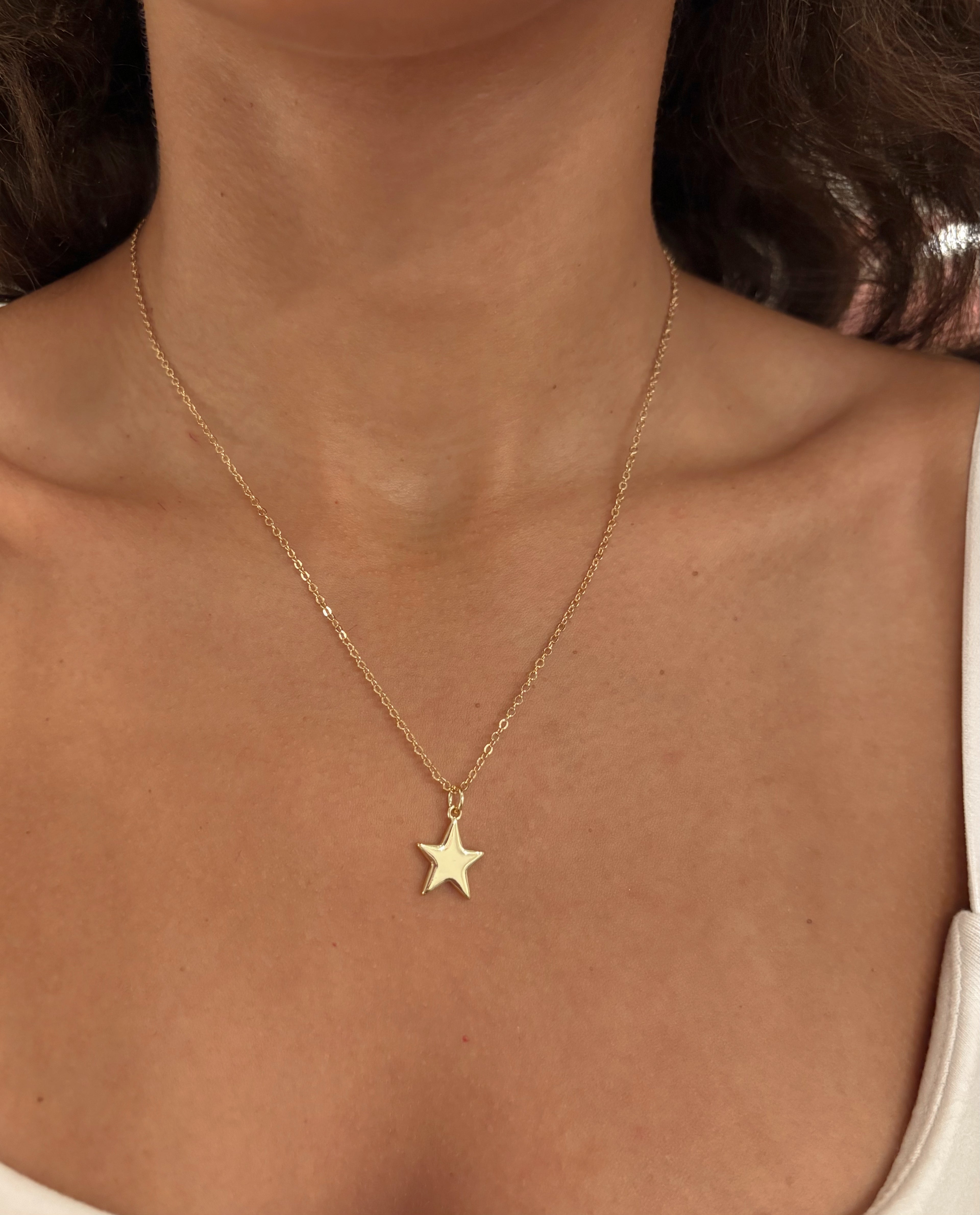 Gold star necklace on a person's neck